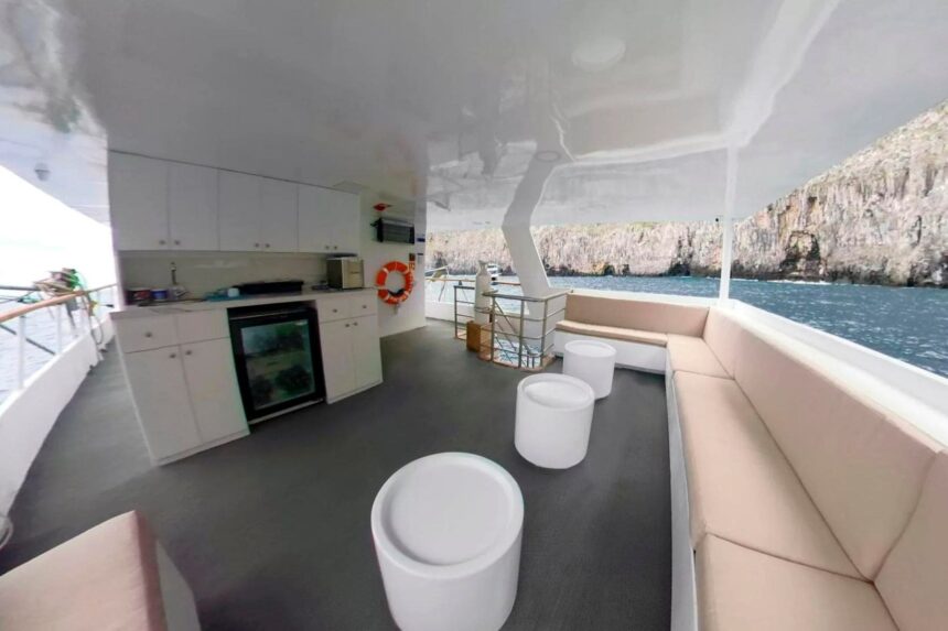 Lounge deck with white cushioned seating and a small bar area on the Aqua