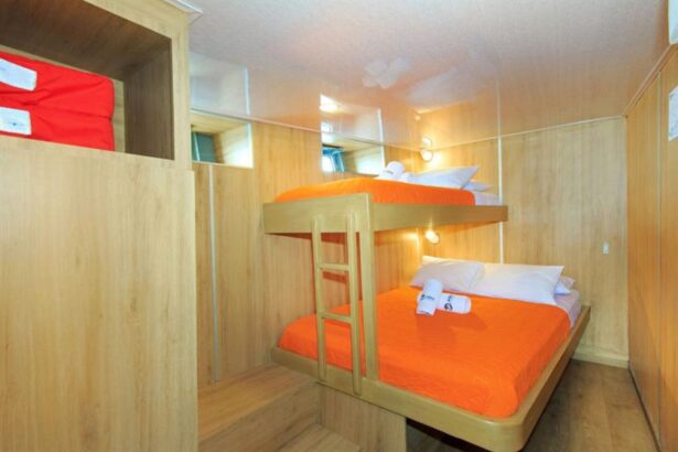 Bunk cabin on the Aqua with orange bedding and a wooden ladder