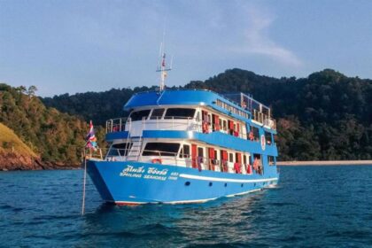 The Smiling Seahorse liveaboard moored close to a green forested shoreline
