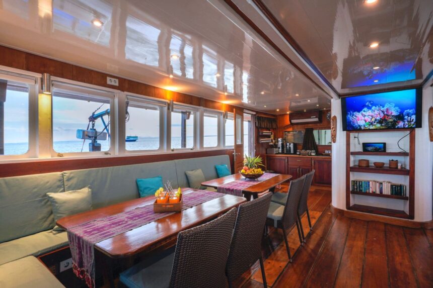 Covered lounge deck with wicker sofas and a stairway aboard the Ambai