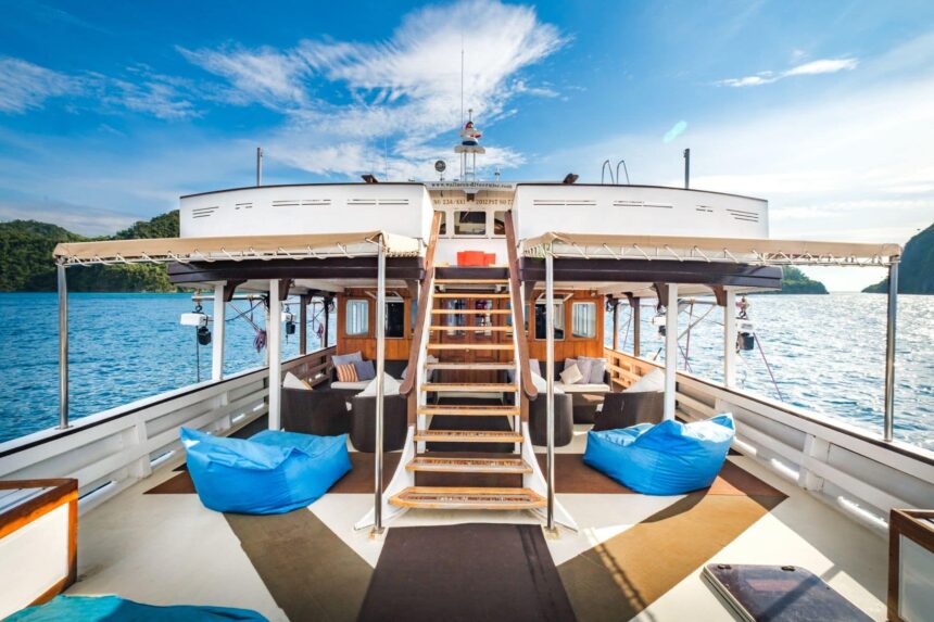 Bunk cabin aboard the Ambai with a yellow-trimmed double bed and wooden fittings