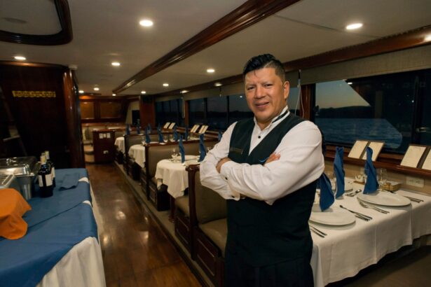 crew member standing with arms crossed in the dining room of the Galapagos Sky