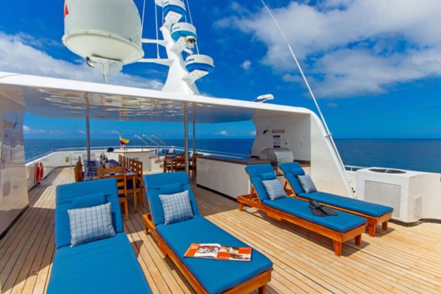 a shaded sundeck with wooden lounge chairs and a dining table on the Calipso