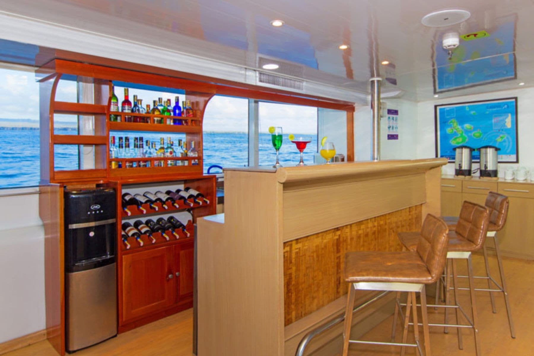 a stocked bar with cocktails and stools aboard the Calipso