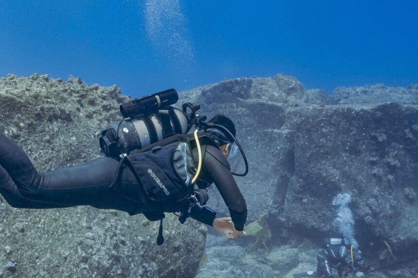 DIVEIN tester diving along a rocky reef with the LEFEET P1 mounted on the back of the tank