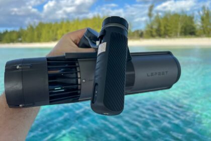 Our tester holding the compact LEFEET P1 sea scooter above turquoise shallows on a tropical shoreline