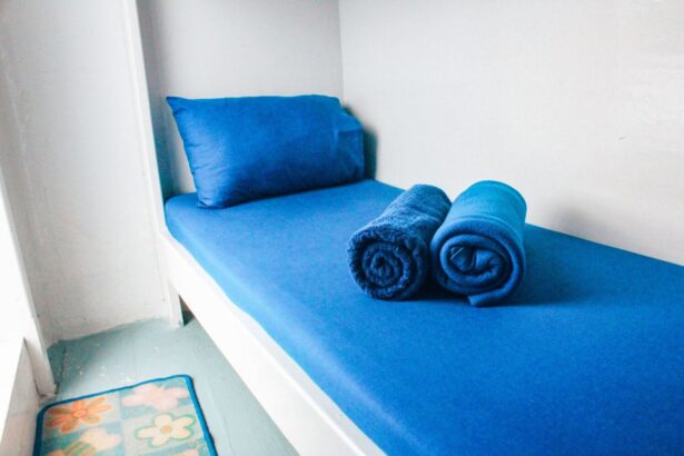 a single blue-cushioned bed in a basic Epica cabin with rolled towels