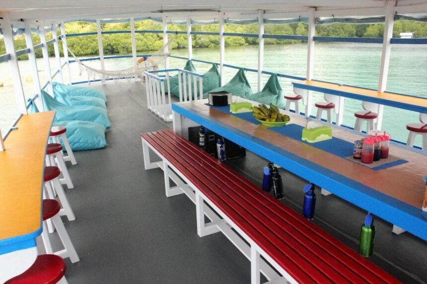 Bean bags and stools line the shaded upper deck of the Epica liveaboard on calm water