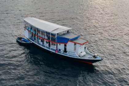 The Epica liveaboard cruising across calm water under its white canopy roof
