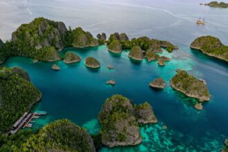 Aerial view of turquoise lagoons and jungle covered karst islands in Raja Ampat