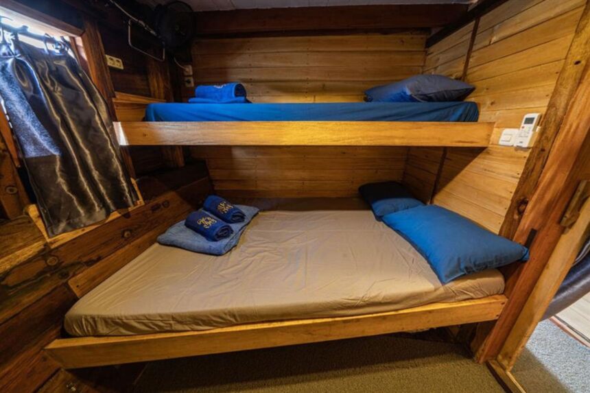 Wooden bunk cabin aboard the Jaya with towels folded on the lower berth