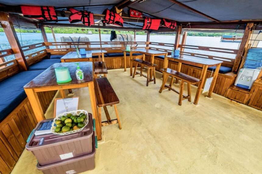 Indoor dining tables and benches set with life jackets hanging above on the Jaya