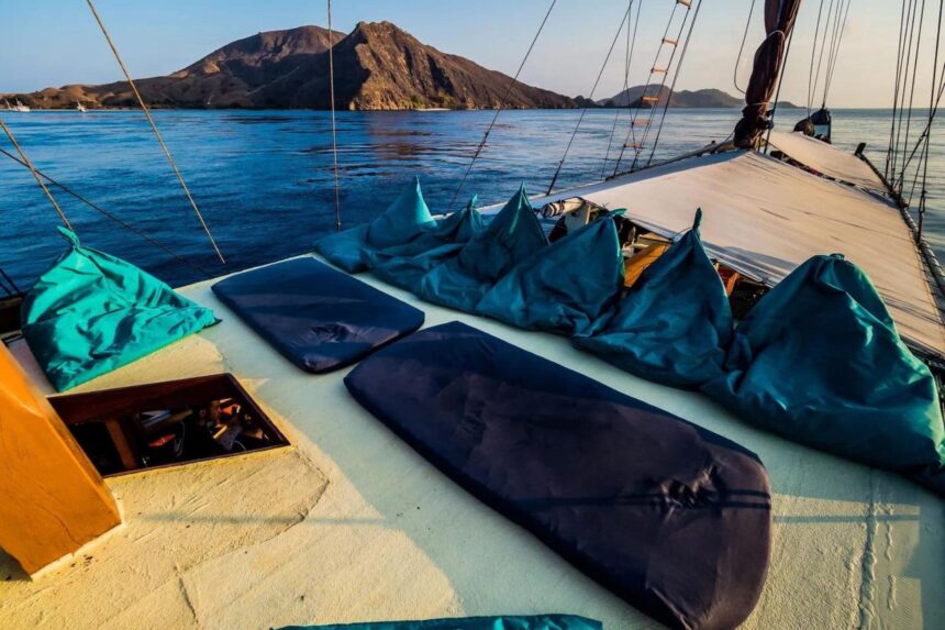Teal bean bags and cushions arranged on the Jaya's sundeck at sunset with an island backdrop