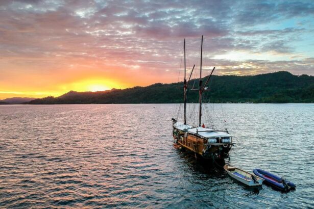The Jaya liveaboard anchored at sunset with its masts silhouetted against the sky