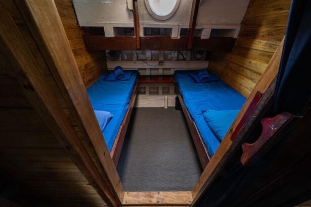 Wooden twin bunk cabin aboard the Jaya with a round porthole overhead