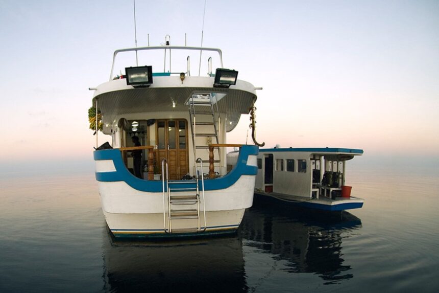 Stern view of the Manthiri liveaboard with its tender boat moored alongside at dusk