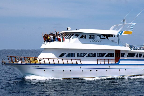 Manthin liveaboard cruising with guests waving from the top deck