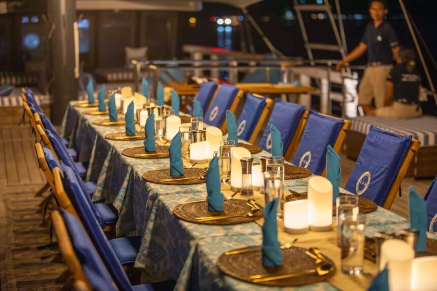 Blue dining chairs set with candles and napkins for an evening meal aboard Scubaspa Zen