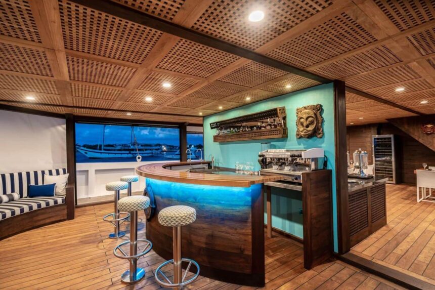 Curved wooden bar with stools lit in blue aboard Scubaspa Zen
