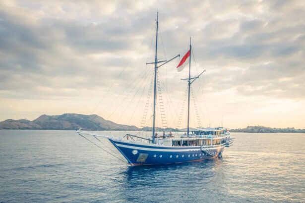 Scubaspa Zen liveaboard boat anchored near hills at dusk with sails rigged and Indonesian flag flying