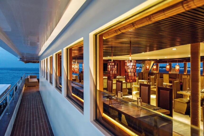 Dining lounge aboard Scubaspa Yin seen through windows along the outer deck