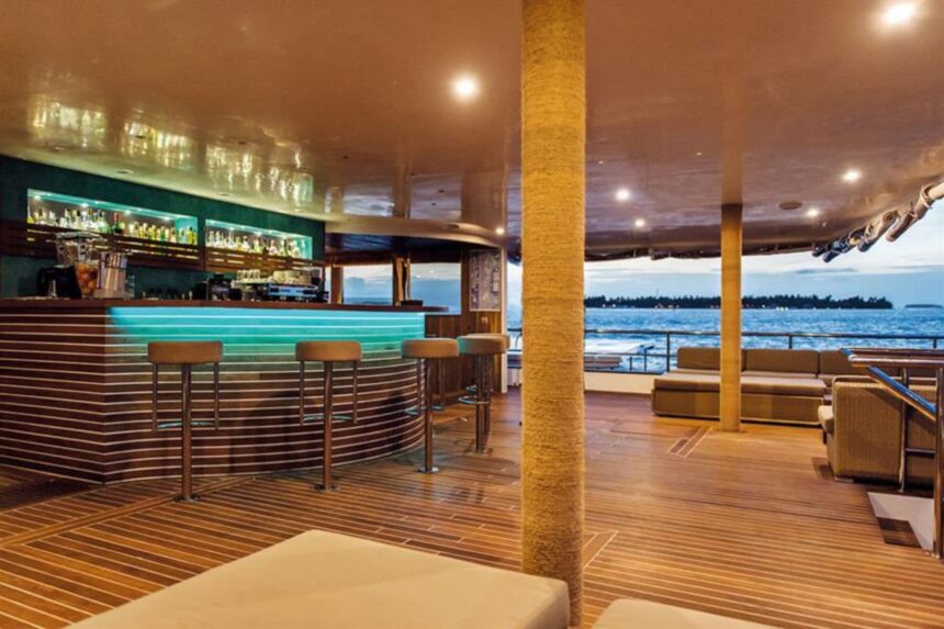 Curved wooden bar with lit countertop and lounge seating aboard Scubaspa Yin