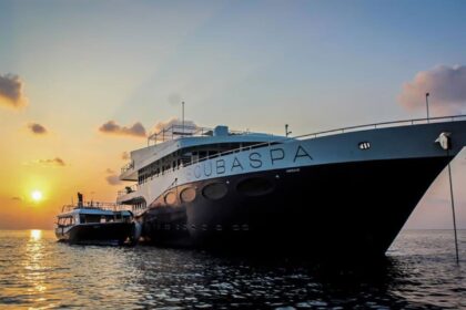 Scubaspa liveaboard yacht hull lit by sunset with a tender boat moored alongside