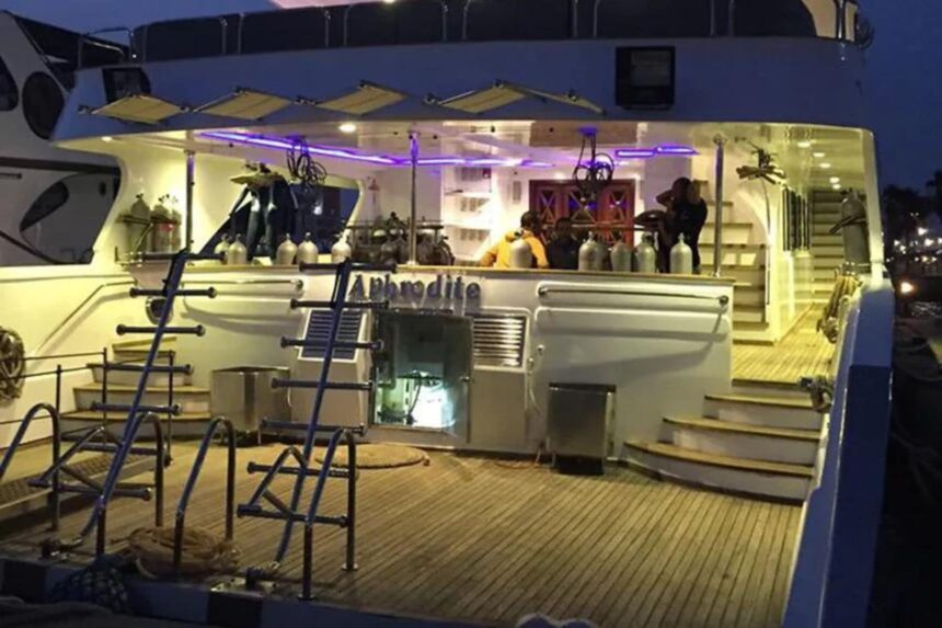 Aphrodite liveaboard deck lit up with divers and tanks at night in port