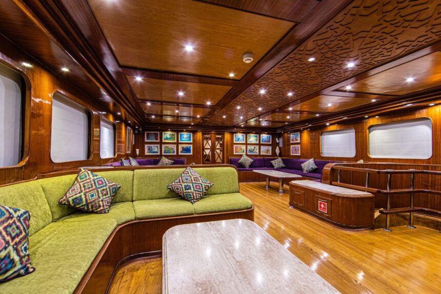 Wood paneled salon with green sofas and framed art aboard the Aphrodite