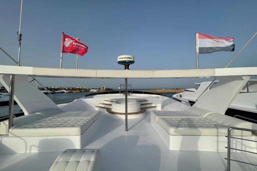 Sun loungers on the bow of the Aphrodite with flags flying against a clear sky