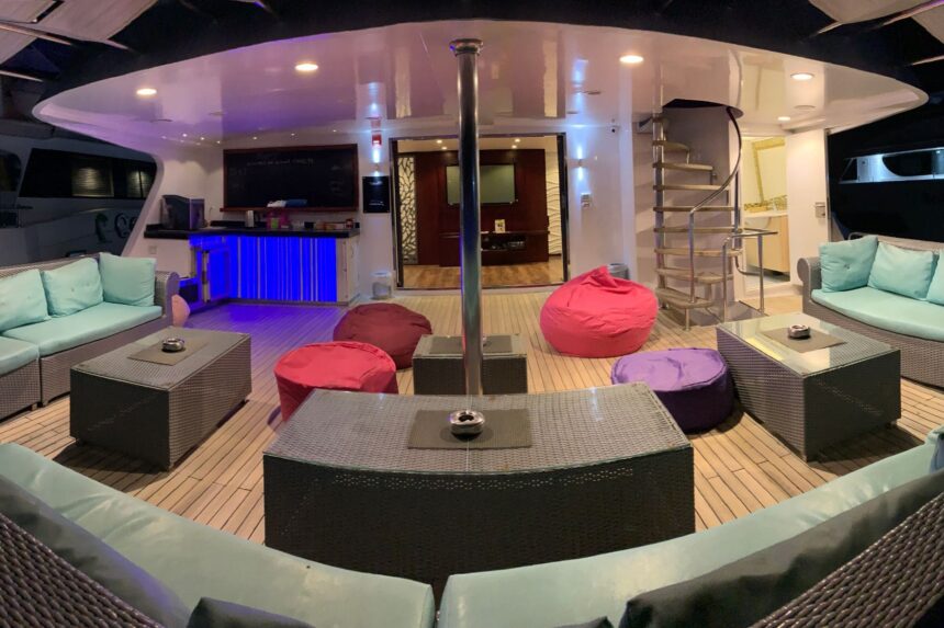Outdoor lounge deck with bean bags and a spiral staircase aboard the Aphrodite at night