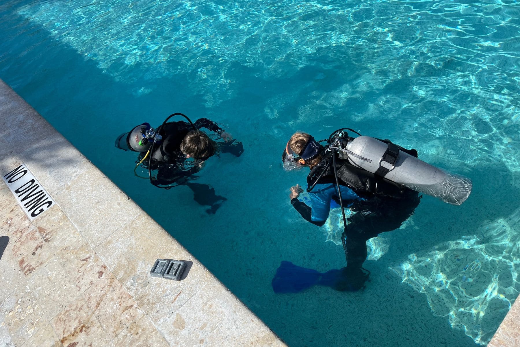 Two children practicing scuba skills underwater in a resort pool at Reef Oasis Dive Club