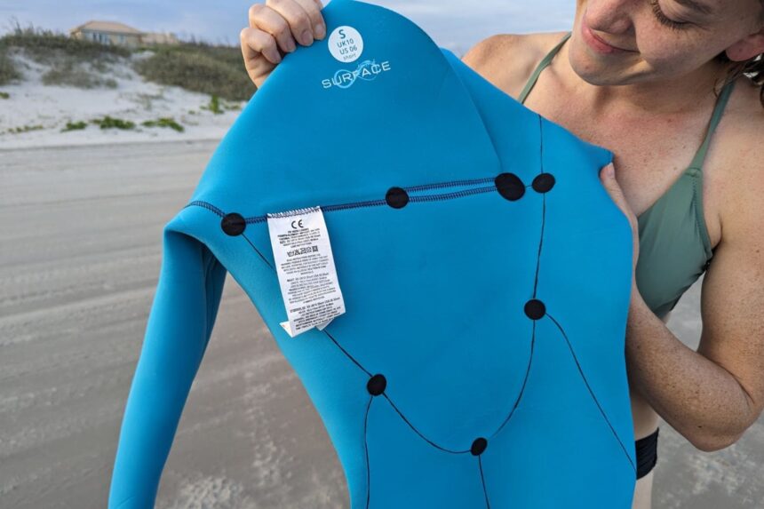 Fourth Element Surface Inner Lining DIVEIN tester holding open the Fourth Element Surface wetsuit to show its blue recycled inner lining and seams