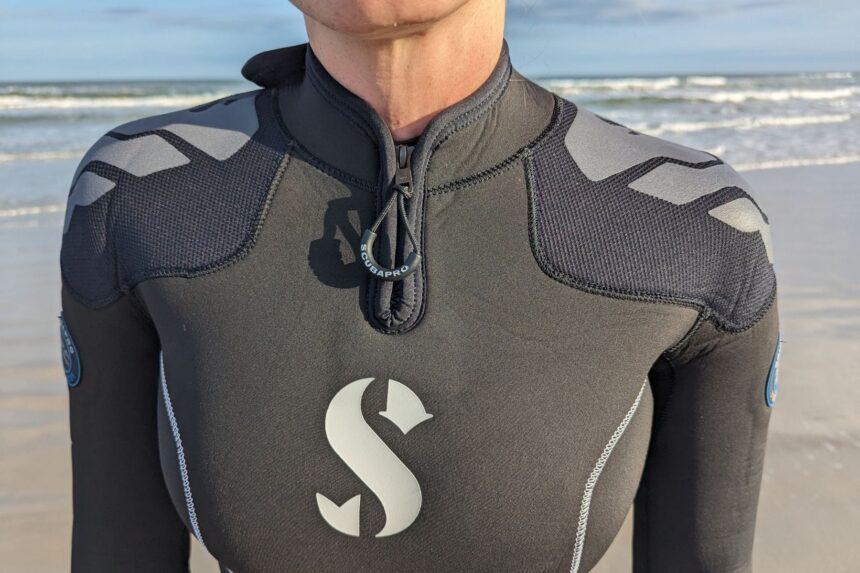 Front chest of the ScubaPro Everflex Yulex wetsuit worn on the beach, showing the neck zip and logo