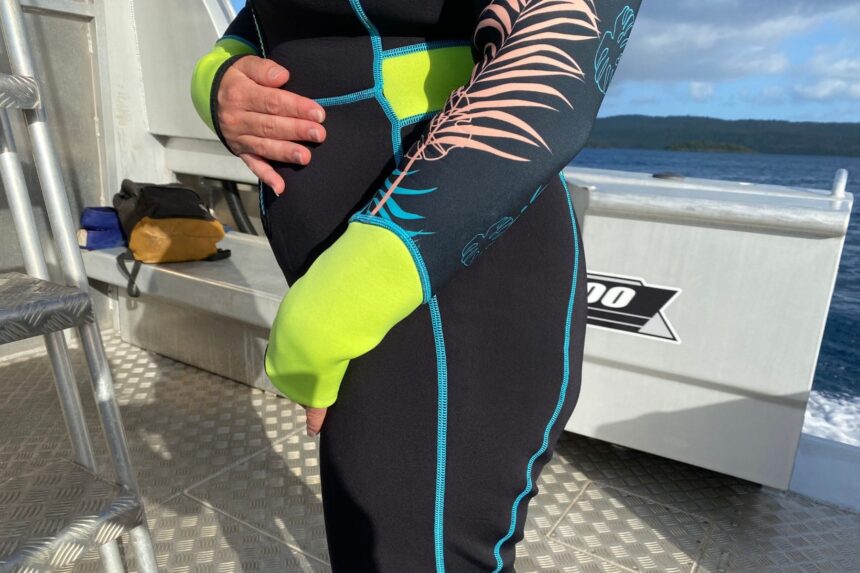 Close-up of the Akona Tropic wetsuit hip and sleeve, with lime cuffs and blue contrast seams