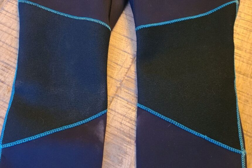Close-up of the reinforced knee pads and blue stitching on the Akona Back Zip Classic wetsuit