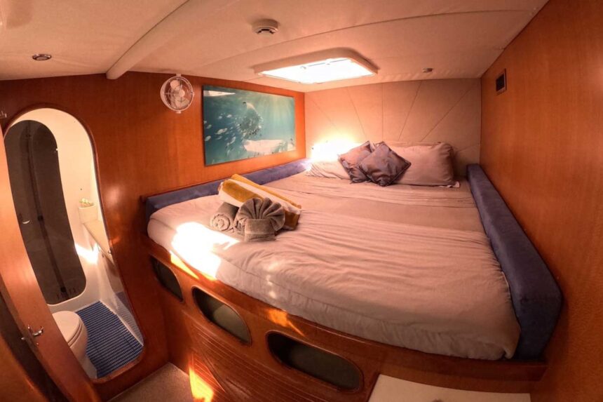 A cabin bedroom aboard the Shore Thing with a queen bed and ensuite bathroom
