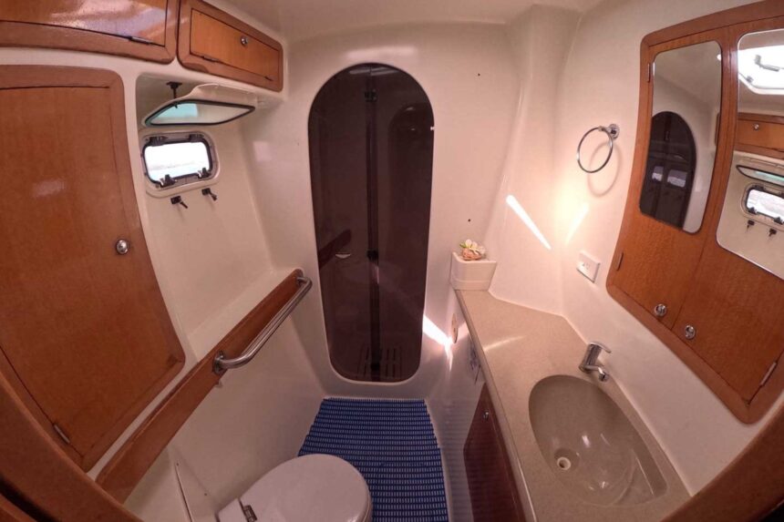 A compact bathroom aboard the Shore Thing with a shower stall and vanity sink