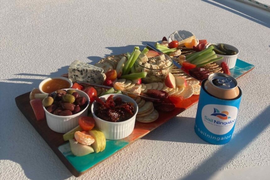 A charcuterie board with cheese, olives, and crackers served on deck