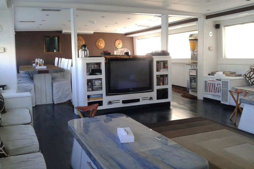 Salon lounge aboard the Aldebaran with a TV and bookshelf
