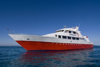 Aldebaran liveaboard yacht with a red hull anchored on open blue water