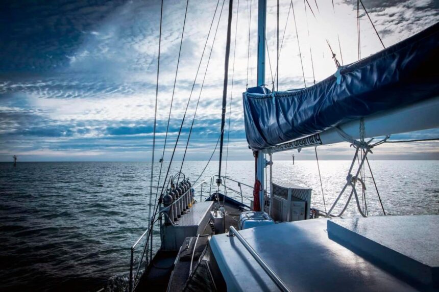 View along the bow of a sailing catamaran under an overcast sky at sea