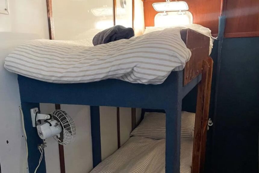 A cabin bunk bed with striped bedding aboard the Coral Sea Dreaming