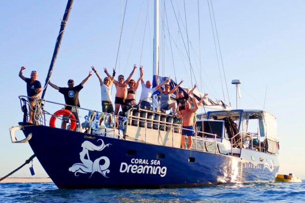 Guests aboard the Coral Sea Dreaming raising their arms in celebration at the boat's stern