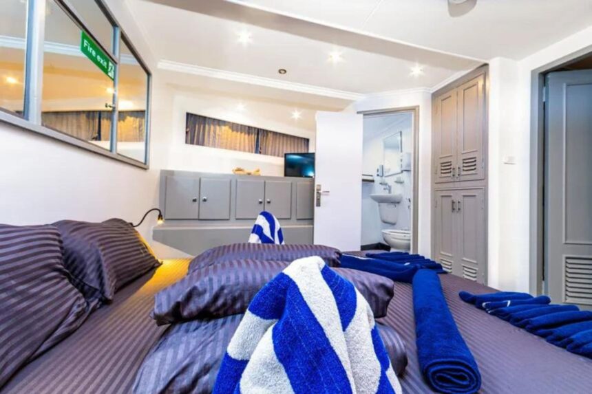 A cabin bed piled with towels next to an ensuite bathroom on the Discovery II