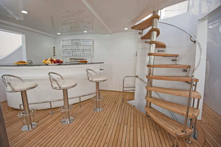 An open-air bar with stools and a spiral staircase aboard the Discovery II