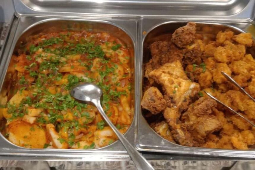 A tray of stewed vegetables and fried chicken pieces served buffet-style