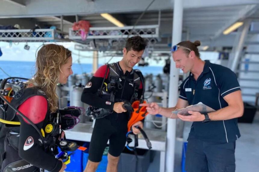 Divers being briefed by a crew member while suited up on the OceanQuest dive deck