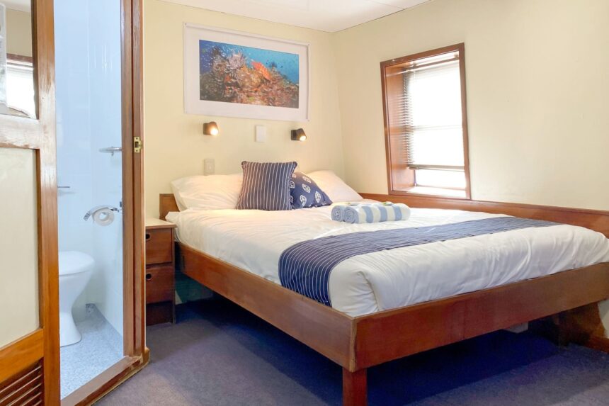 Twin cabin bedroom on OceanQuest with reef artwork above the bed