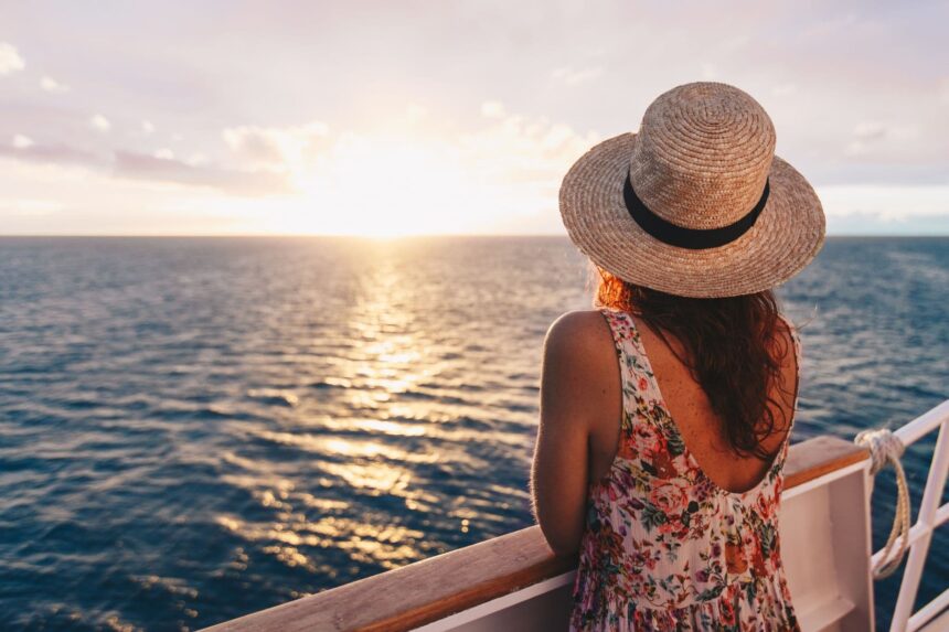 Woman in a straw hat watching the sunset from the back of the boat